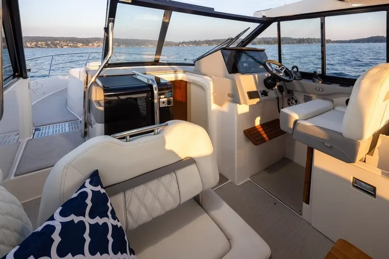 Slide: The Image of 2024 Regal 36 Grande Coupe interior with luxurious seating and modern helm, overlooking serene waters. - 13