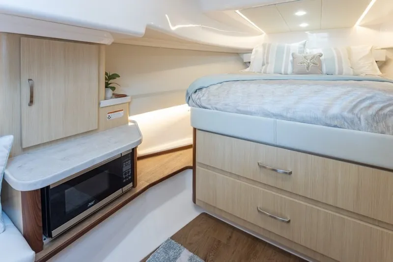 Slide: The Image of 2024 Regal 36 Grande Coupe interior with bed, microwave, and wooden cabinetry. - 7