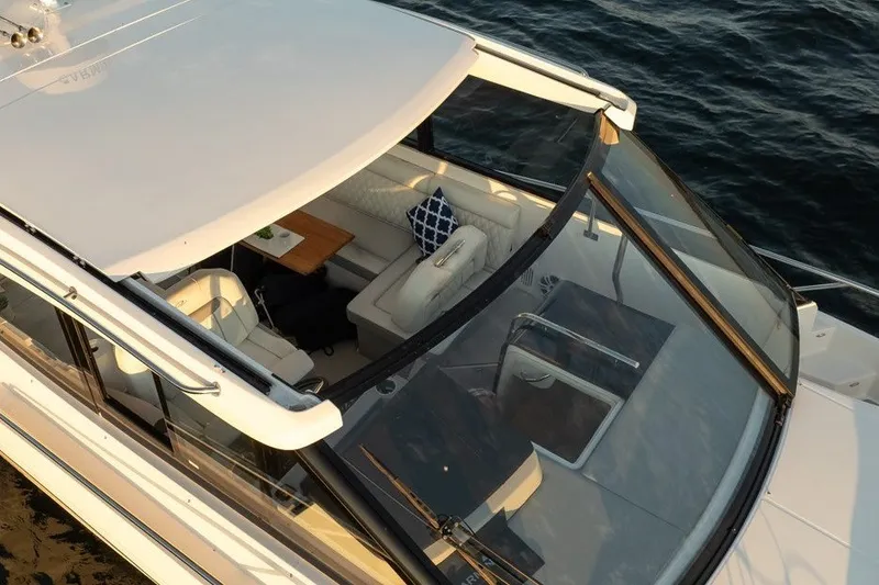 Slide: The Image of 2024 Regal 36 Grande Coupe yacht interior with seating and table, on calm water. - 26