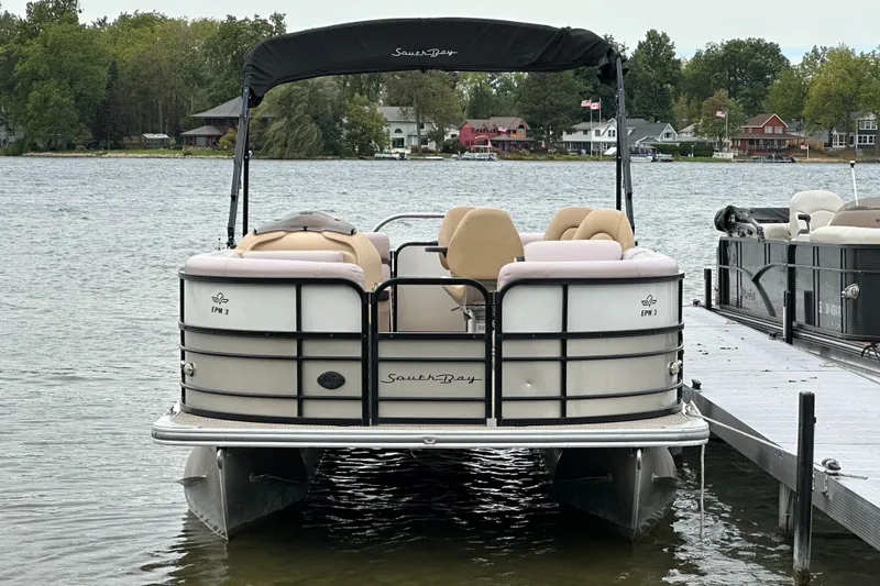 Slide: The Image of A 2019 South Bay S224SB225 pontoon boat docked by a pier, surrounded by a calm lake. - 3