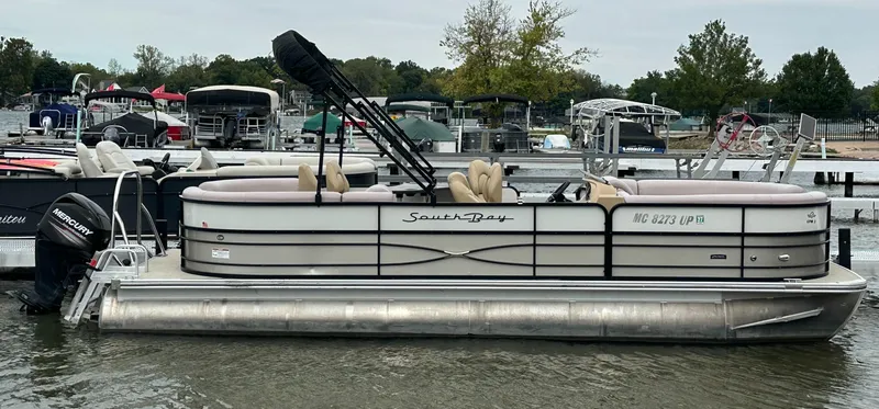 The Image of A 2019 South Bay pontoon boat is on the water, surrounded by other boats at the dock. - 0