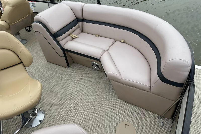 Slide: The Image of A sleek pontoon boat with beige upholstery and carpeted flooring on calm water. - 6