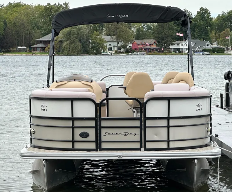 Slide: The Image of A 2019 South Bay pontoon boat docked, surrounded by water and trees. - 2