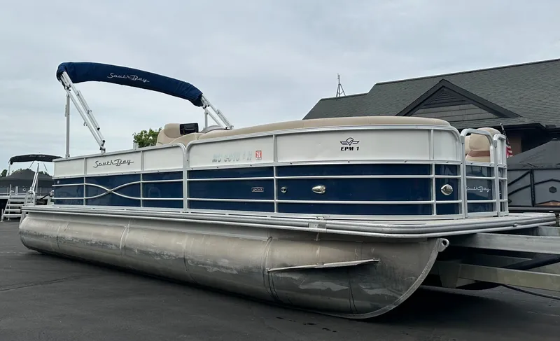 Slide: The Image of A 2018 South Bay S224CR pontoon boat on a trailer, featuring a blue and white design. - 20