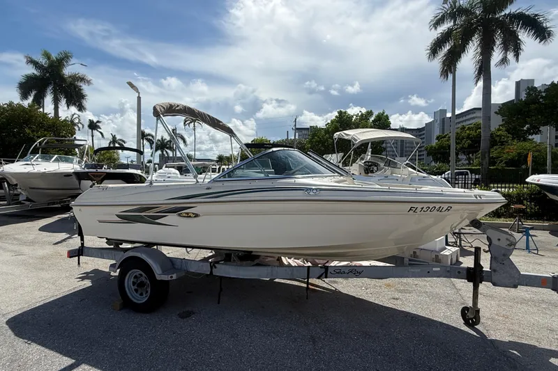 The Image of 2001 Sea Ray 180 Bow Rider boat on trailer, parked outdoors under a sunny sky. - 1