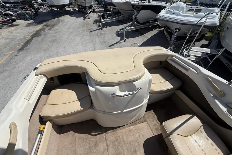 Slide: The Image of 2001 Sea Ray 180 Bow Rider interior with beige seating, parked among other boats. - 4