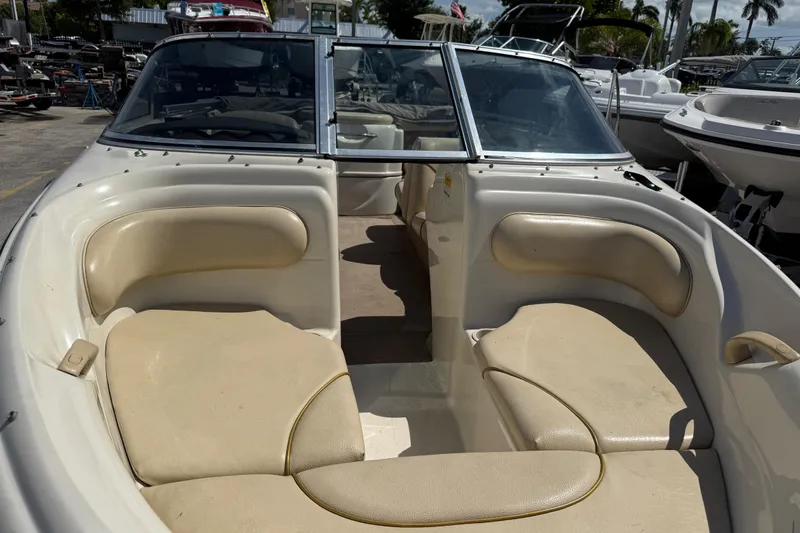 Slide: The Image of 2001 Sea Ray 180 Bow Rider interior with beige seating, docked among other boats. - 14