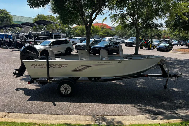 Slide: The Image of 2012 Alumacraft Fisherman 160 Tiller boat on trailer in parking lot. - 1
