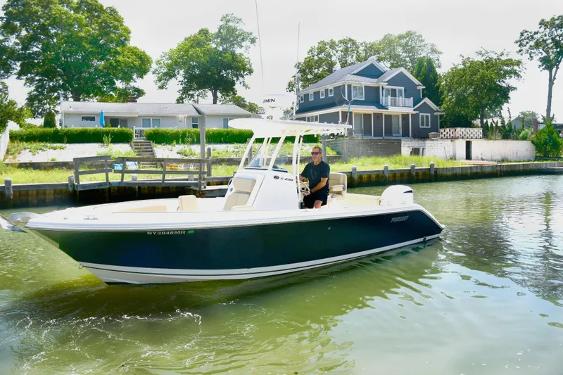 The Image of 2020 Pursuit C 238 Center Console boat cruising near waterfront homes. - 0