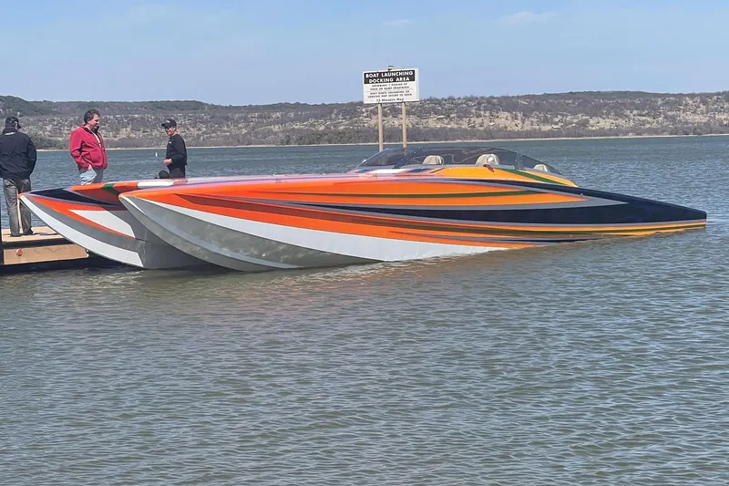 Slide: The Image of High-performance 2013 Skater 46 powerboat with vibrant orange and black design docked on a lake. - 1