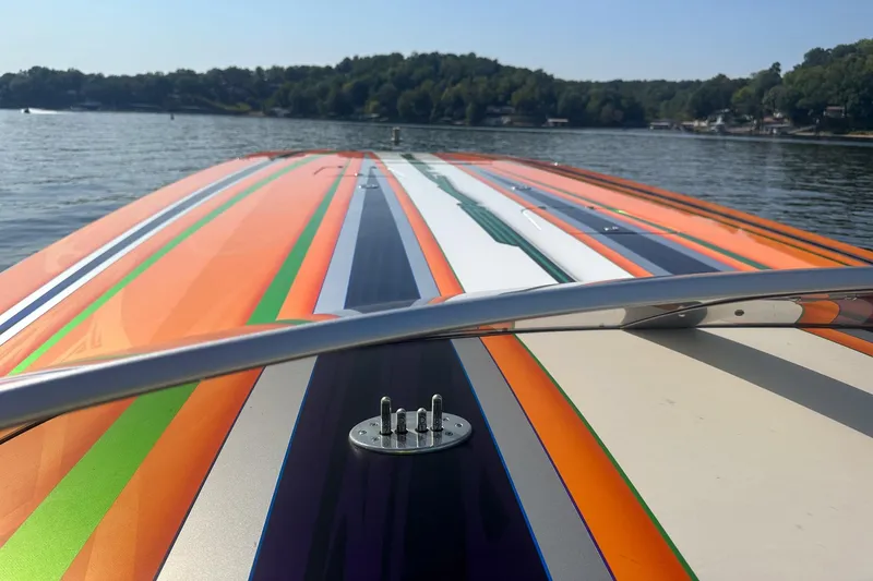Slide: The Image of Colorful Skater 46 boat from 2013 on a serene lake with wooded shoreline. - 12