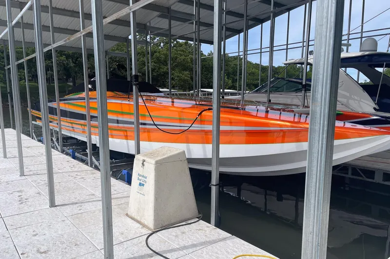 Slide: The Image of Orange and white Skater 46 boat docked, 2013 model, under a covered marina. - 4