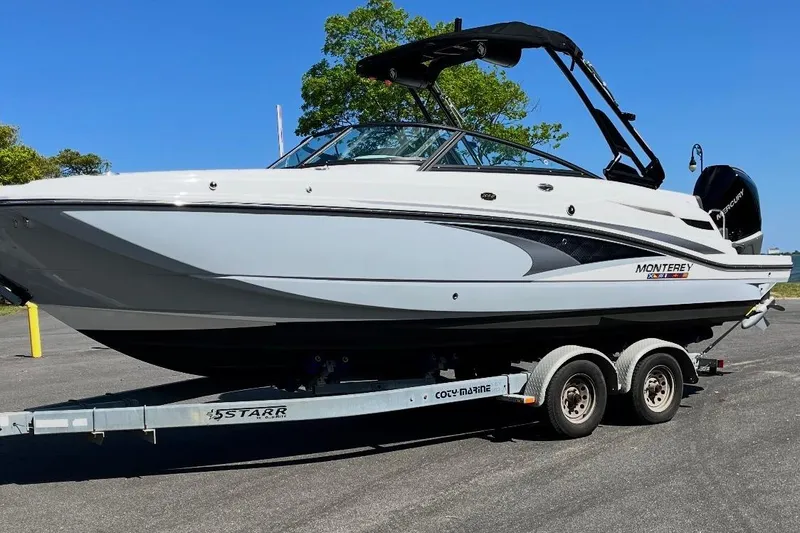 Slide: The Image of 2024 Monterey M-65 boat on trailer, sleek design, parked outdoors under clear blue sky. - 2
