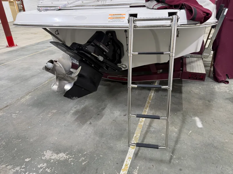Slide: The Image of A 2006 Crownline 220 EX with a swim ladder and propeller in a warehouse. - 21
