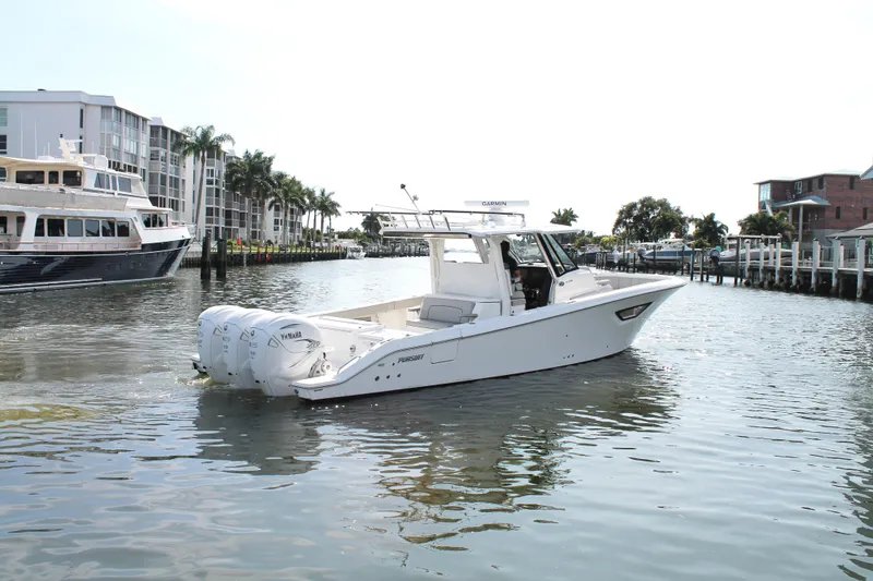 Slide: The Image of 2023 Pursuit S 378 Sport boat cruising in a marina with modern buildings and palm trees. - 10