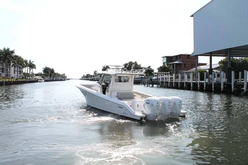 Slide: The Image of 2023 Pursuit S 378 Sport boat cruising on a sunny canal with palm trees. - 7