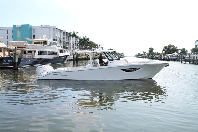 Slide: The Image of 2023 Pursuit S 378 Sport boat cruising in a marina with modern buildings in the background. - 11