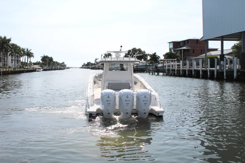 Slide: The Image of 2023 Pursuit S 378 Sport boat cruising on a sunny canal with palm trees. - 8