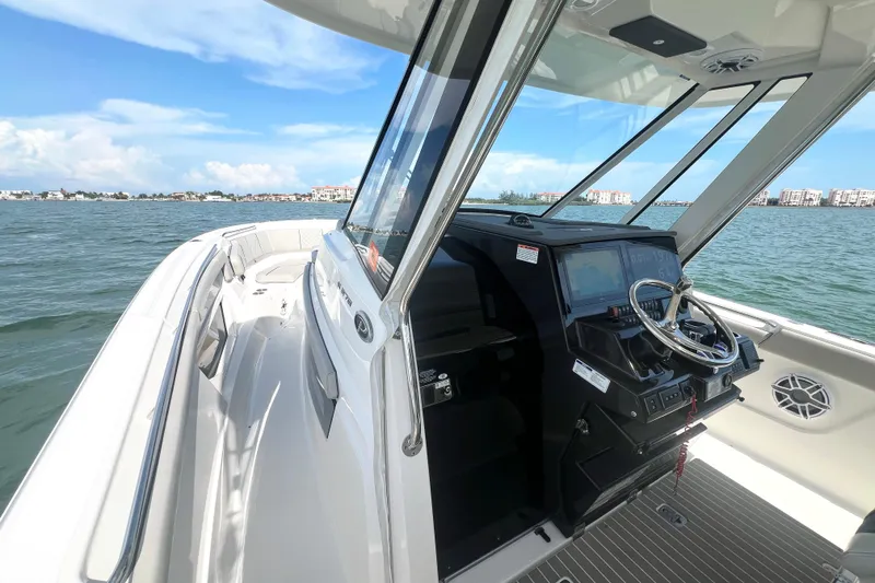 Slide: The Image of 2023 Pursuit S 378 Sport boat interior with steering wheel, dashboard, and ocean view. - 33