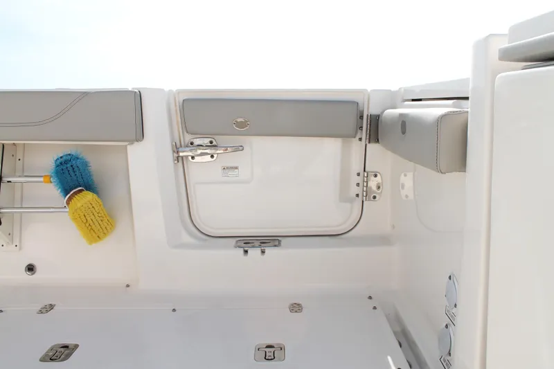 Slide: The Image of 2023 Pursuit S 378 Sport boat interior with storage compartment and cleaning brush. - 23