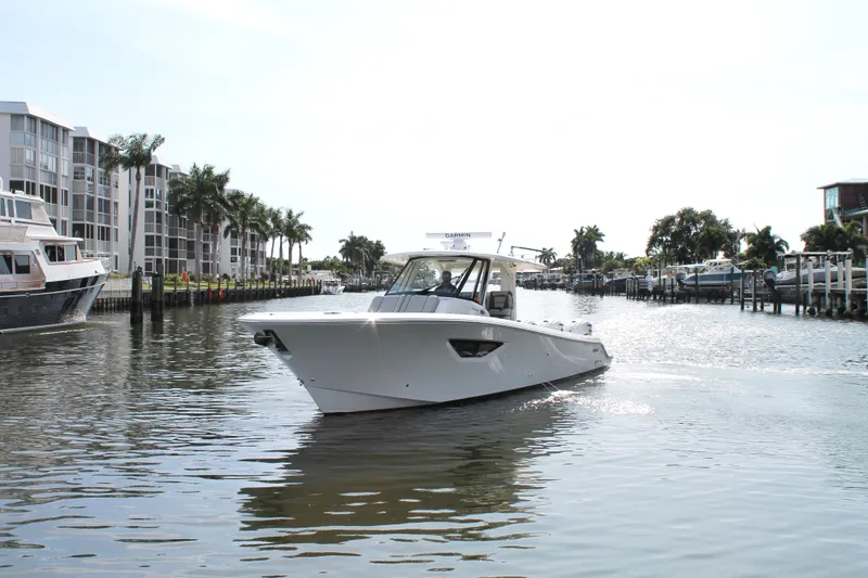 Slide: The Image of 2023 Pursuit S 378 Sport boat cruising in a sunny marina with palm trees and buildings. - 4