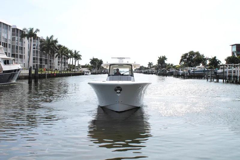 Slide: The Image of 2023 Pursuit S 378 Sport boat cruising in a scenic canal with palm trees. - 3