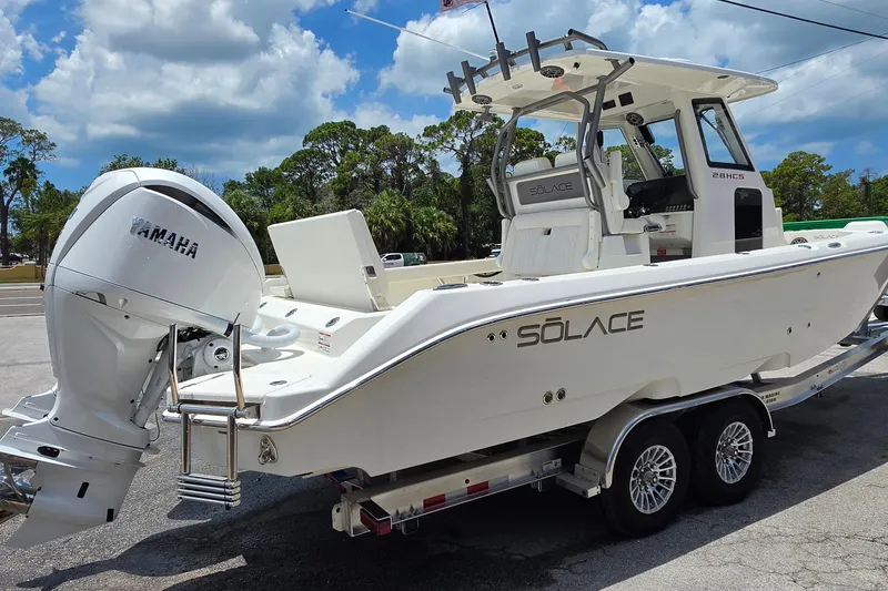 Slide: The Image of 2027 Solace 28HCS boat on trailer with Yamaha outboard motor, under a partly cloudy sky. - 5
