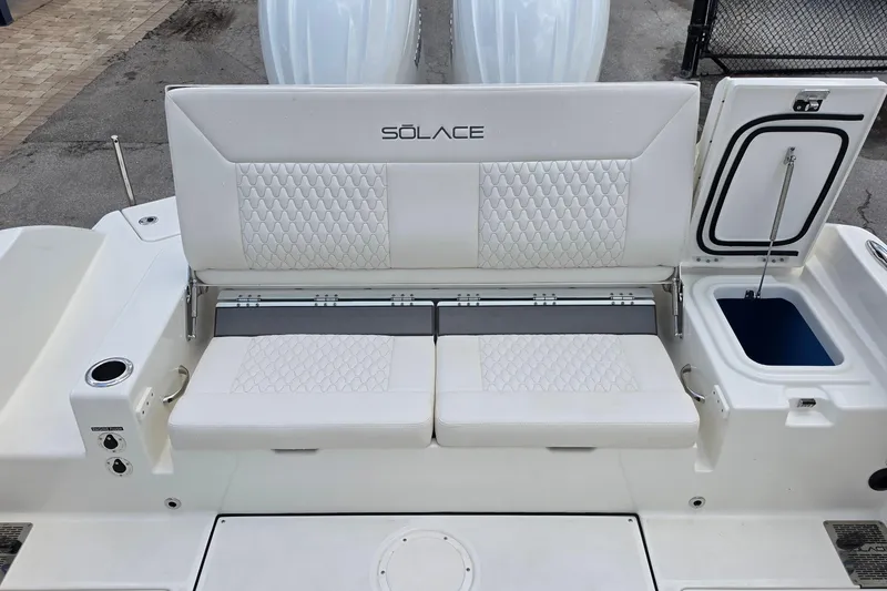 Slide: The Image of 2027 Solace 28HCS boat seating area with white cushioned seats and storage compartment. - 12