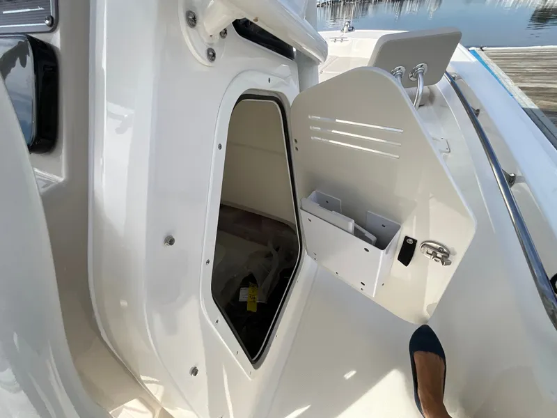 Slide: The Image of An open storage compartment on a Boston Whaler 210 Montauk boat, with a view of the dock. - 13