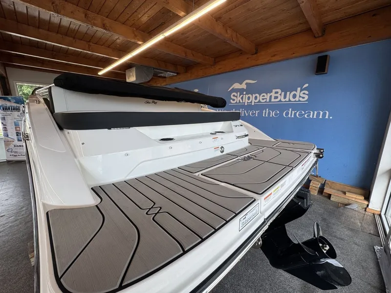 Slide: The Image of The image shows the stern of a 2026 Sea Ray SPX 210 boat in a showroom. - 2
