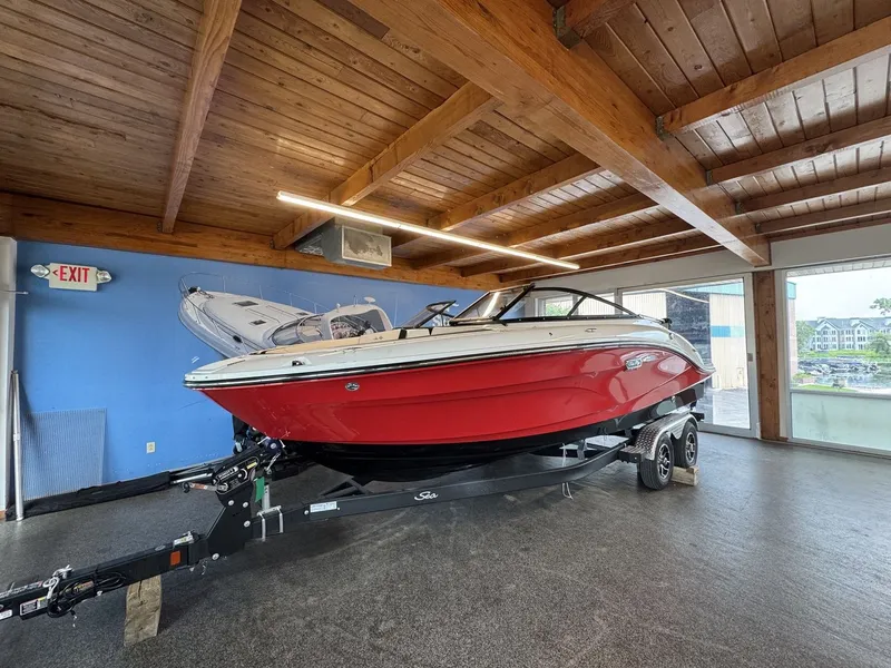 Slide: The Image of A red 2026 Sea Ray SPX 210 boat on a trailer inside a wooden building. - 1