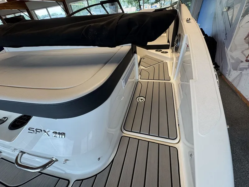 Slide: The Image of The image shows the deck of a Sea Ray SPX 210 boat with gray flooring and black upholstery. - 4