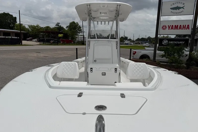 Slide: The Image of 2026 BlackJack 256 Coastal boat with white seating, displayed outdoors near dealership signs. - 6