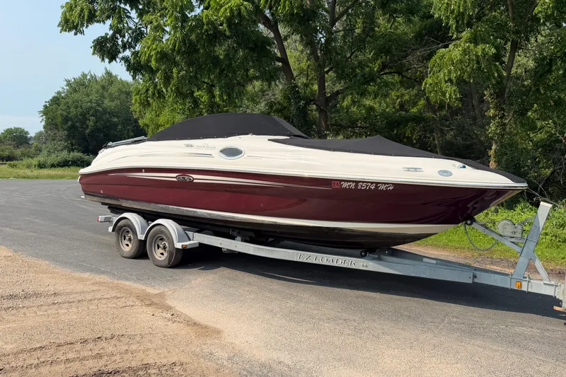 Slide: The Image of 2009 Sea Ray 240 Sundeck boat on trailer, parked outdoors near trees. - 4
