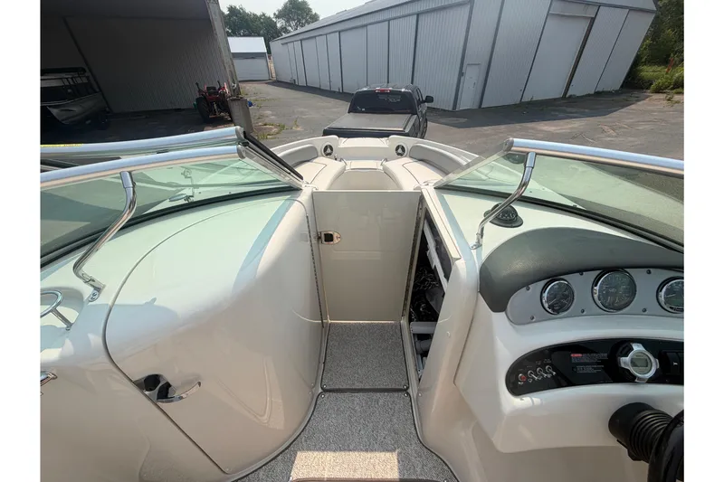 Slide: The Image of 2009 Sea Ray 240 Sundeck interior with dashboard and open compartment, parked near storage units. - 8