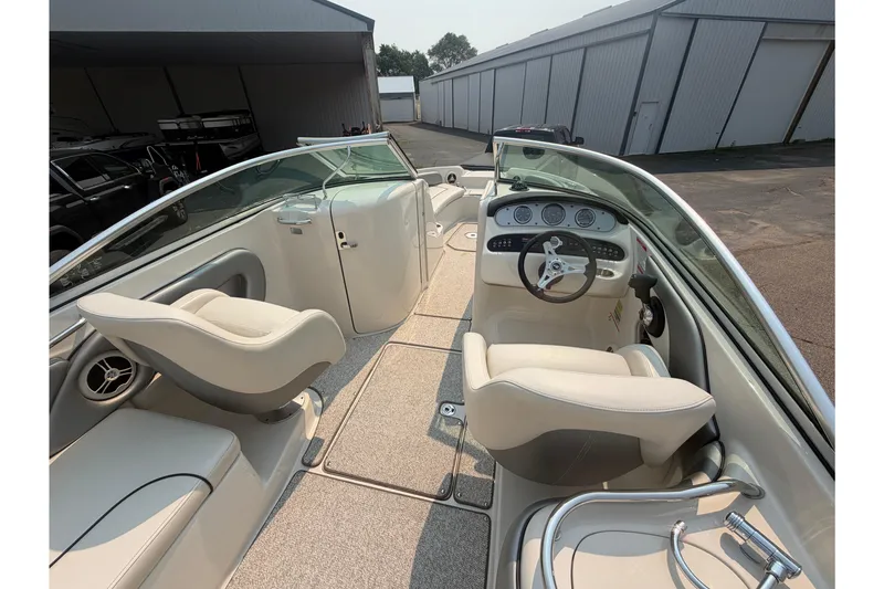 Slide: The Image of 2009 Sea Ray 240 Sundeck interior with helm, seating, and dashboard in a marina setting. - 17