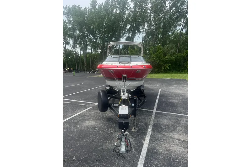 Slide: The Image of 2018 Formula 270 Bowrider boat on trailer in parking lot, surrounded by trees. - 6