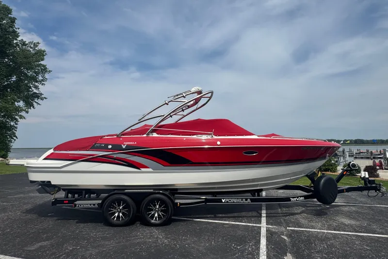 Slide: The Image of 2018 Formula 270 Bowrider boat with red cover on trailer by the water. - 2