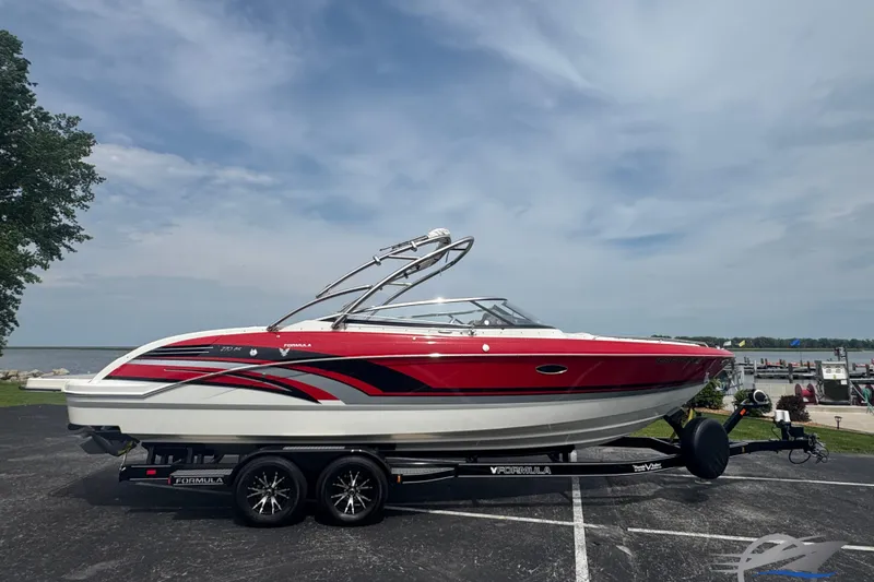 The Image of 2018 Formula 270 Bowrider boat on trailer, red and white design, parked near a lake. - 0