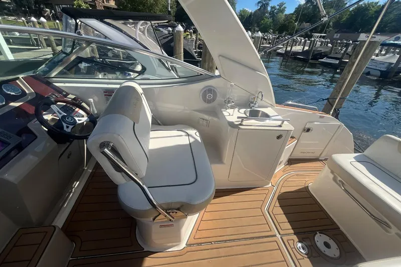 Slide: The Image of 2010 Sea Ray Sundancer 260 boat interior with helm, seating, and kitchenette by the water. - 17