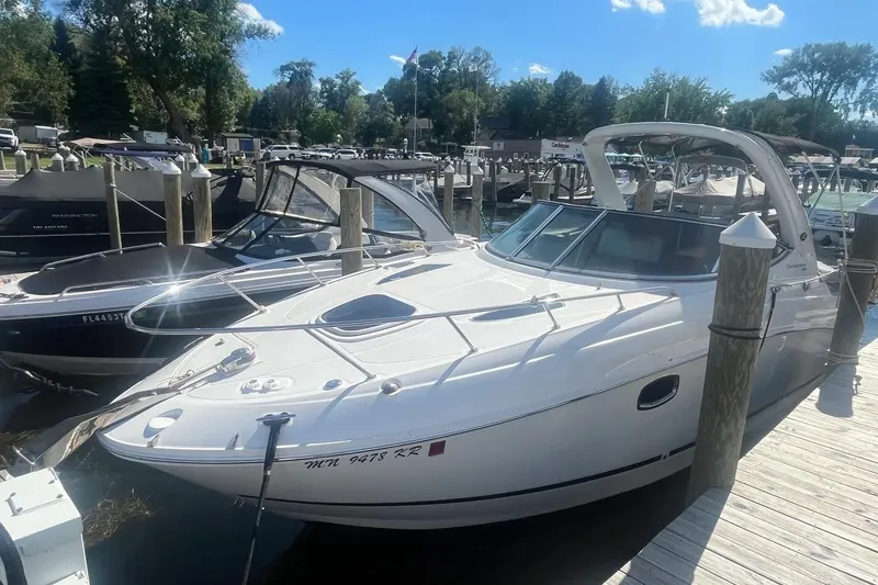 The Image of 2010 Sea Ray Sundancer 260 docked at a marina under a clear blue sky. - 0
