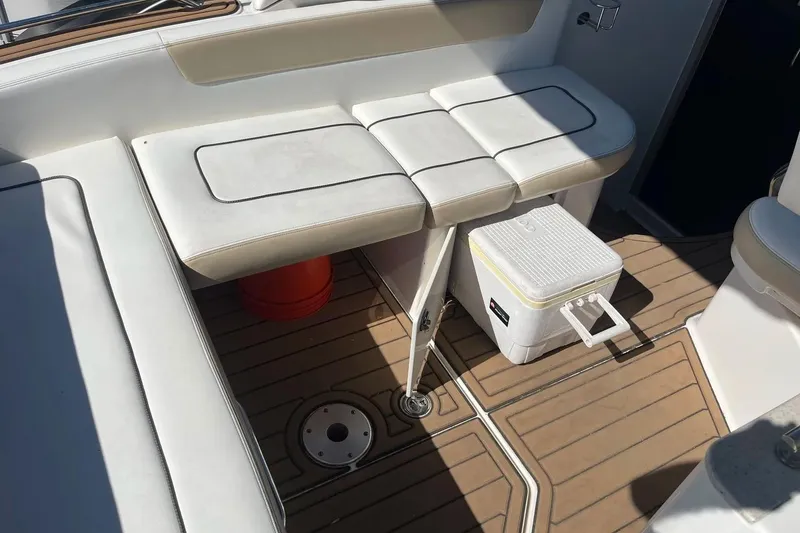 Slide: The Image of 2010 Sea Ray Sundancer 260 boat interior with white seating and wooden flooring. - 10