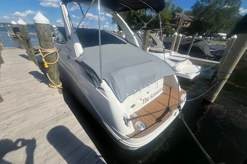 Slide: The Image of 2010 Sea Ray Sundancer 260 docked, covered, with wooden deck, sunny day, marina background. - 2