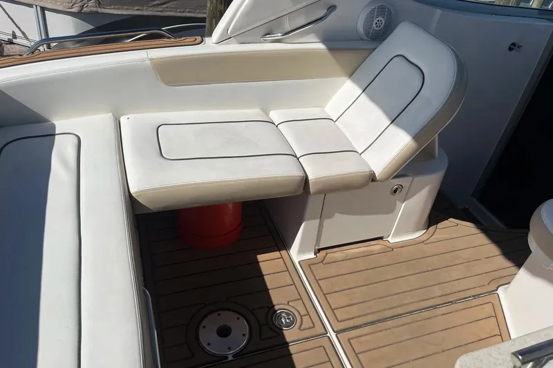Slide: The Image of Interior seating of 2010 Sea Ray Sundancer 260 boat with white cushions and wood flooring. - 11
