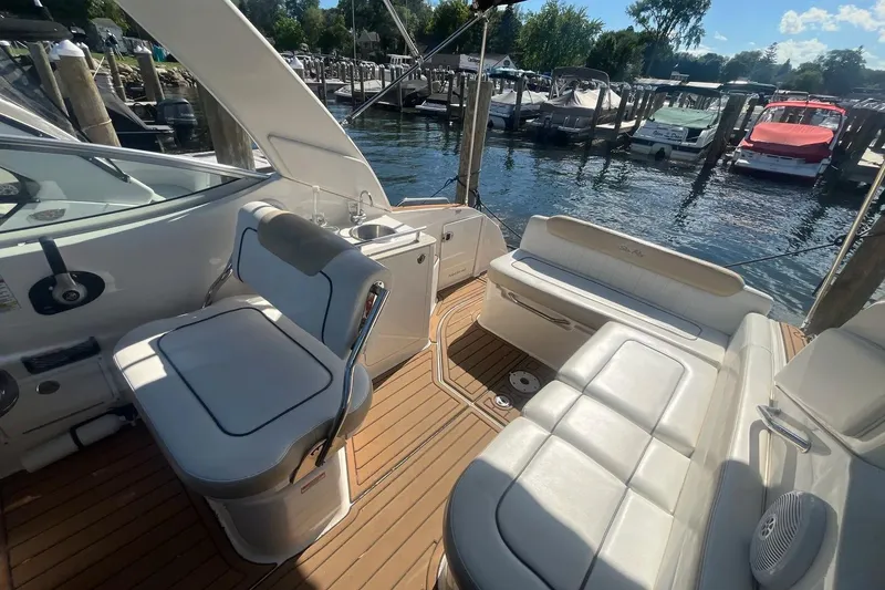 Slide: The Image of 2010 Sea Ray Sundancer 260 boat interior with white seating and wooden deck at marina. - 12
