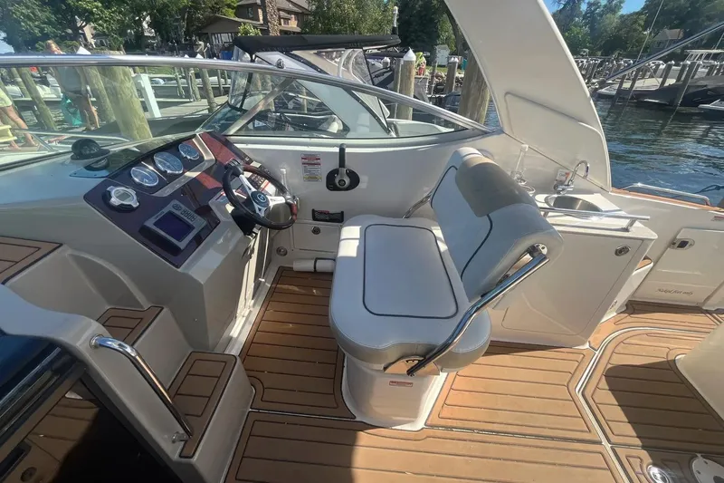 Slide: The Image of 2010 Sea Ray Sundancer 260 cockpit with helm, seating, and sink, docked by the water. - 16