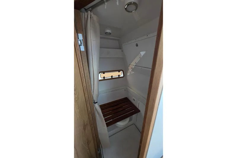 Slide: The Image of 2027 Bertram 39 CC boat interior bathroom with wooden seat and porthole window. - 41