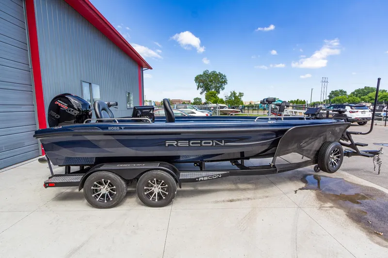 Slide: The Image of 2026 Recon 2085 T boat on trailer, parked outdoors near a building. - 2