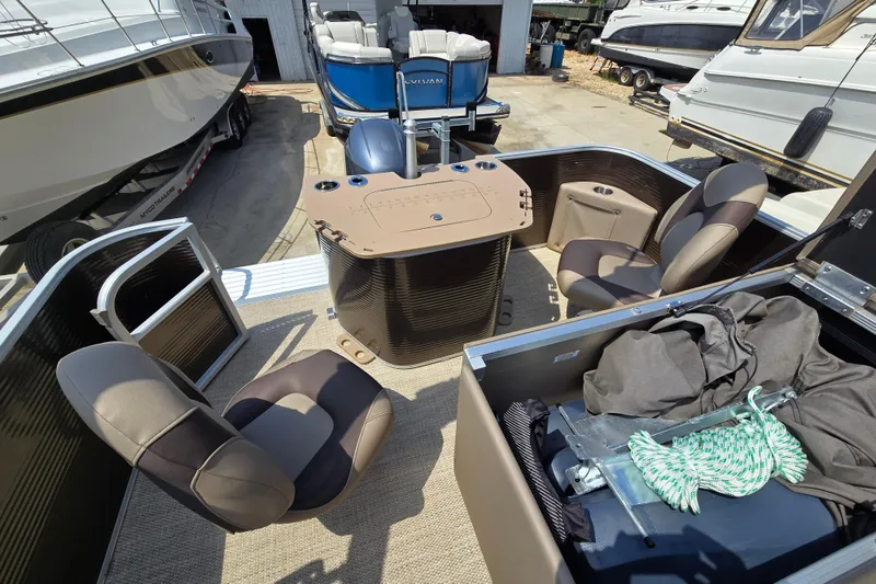 Slide: The Image of 2024 Bennington S22 pontoon boat interior with seating and storage, docked among other boats. - 19