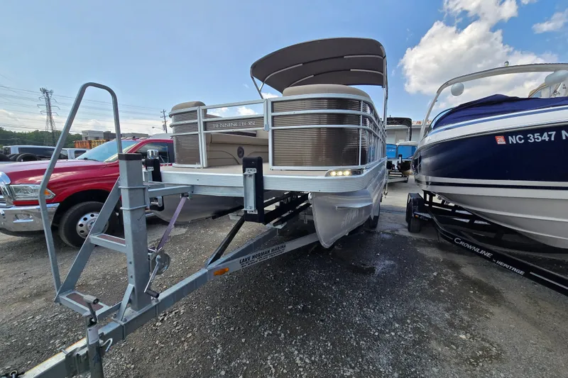 Slide: The Image of 2024 Bennington S22 pontoon boat on trailer, parked outdoors under a blue sky. - 4